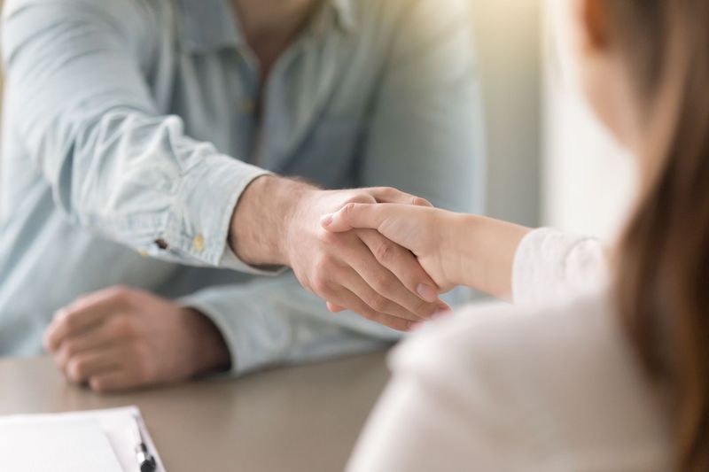 Ilustrasi berjabat tangan Businessman shaking female hand above the table. Business agreement and partnership concept. Partners closing a deal, view over the shoulder. Formal greeting gesture, effective negotiations