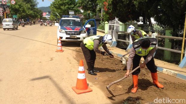 Polisi membersihakn lumpur yang memenuhi jalan/