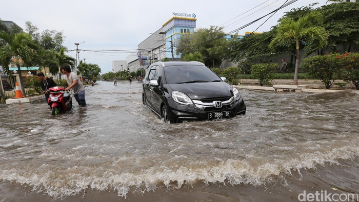 Warga beraktivitas di tengah banjir air laut pasang (rob) di Pelabuhan Nizam Zaman, Muara BAru, Jakarta Utara., Selasa (5/12/2017). Rob tinggi membuat tanggul tidak mampu menahan air laut sehingga membanjiri jalanan setinggi 50 hingg 70an cm. Sejumlah kendaraan roda dua mogok lantaran memaksakan menembus banjir.