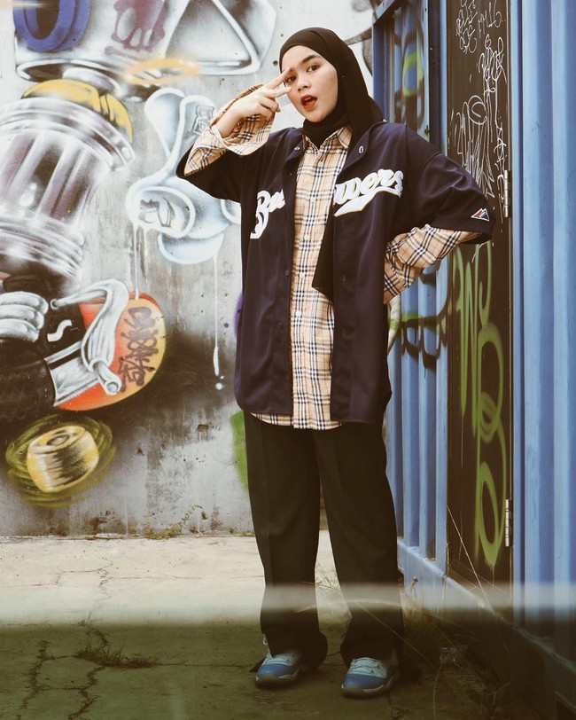  Sivia memang suka menggunakan double pakaian. Kali ini, ia memakai kemeja kotak-kotak dibalut baju lengan pendek sebagai luaran. Celana longgar hitam mampu menutupi lekuk tubuh. Foto: Dok. Instagram @siviazizah