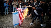 Tampak seorang pria tengah menyulut api membakar kedua bendera tersebut. Sementara sejumlah demonstran lain tampak menyaksikan.  (Foto: Dok. REUTERS/Mohammed Salem)