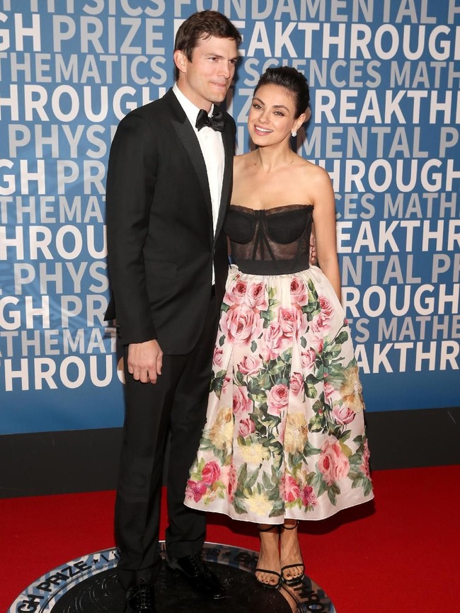 Malam itu, Mila tampak anggun dalam balutan gaun floral dengan bodice korset Dolce & Gabbana. Sementara Ashton gagah dengan tuksedo hitam. (Foto: Jesse Grant/Getty Images)