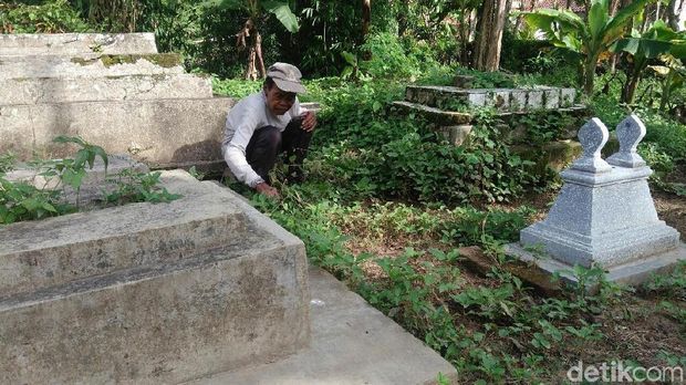 Mbah Waki membersihkan makam.