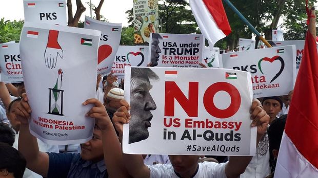 Massa membawa poster berisi kecaman terhadap Donald Trump