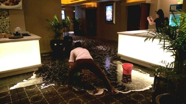 Petugas membersihkan genangan air di Bioskop XXI Planet Hollywood