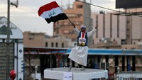 Seorang pria Irak melambaikan bendera Irak yang dibawanya saat perayaan kemenangan atas ISIS. Foto: REUTERS/Thaier Al-Sudani