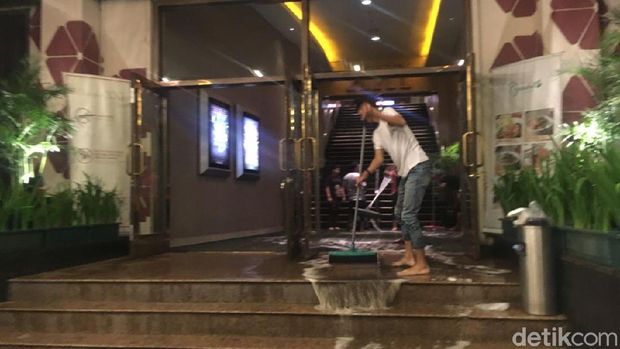 Petugas sedang membersihkan area lobby bioskop