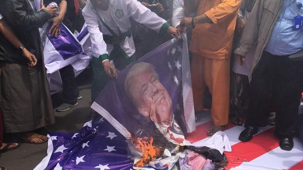 Pendemo juga membakar bendera AS.