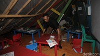 Agus Suprianto turut serta membereskan peralatan anak-anak sekolah usai terjadi atap sekolah roboh yang tertimpa batang pohon besar itu.