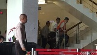 Dia tampak dituntun petugas KPK menaiki tangga keramat menuju ke lantai 2 di mana ruang penyidikan berada.