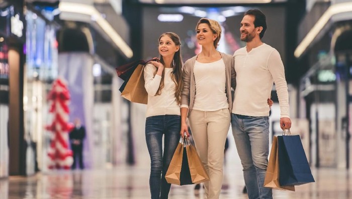 Beautiful parents and their daughter are holding shopping bags and smiling while doing shopping in mall