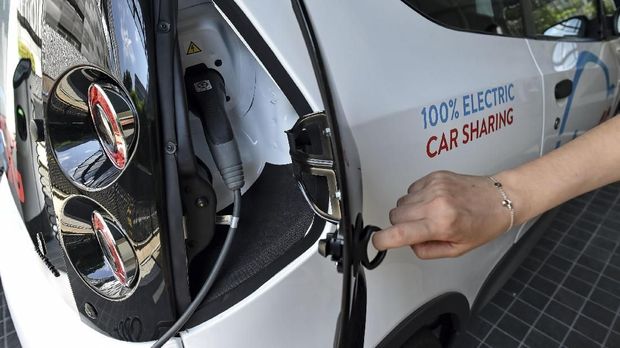 This photograph taken on September 26, 2017 shows a staff member displaying the charging compartment of an electric Bluecar ahead of the launch of a BlueSG office, a subsidiary of France's Bollore Group, in Singapore.The electric car-sharing service will launch in Singapore in December, in what the company behind the scheme said on September 27 was a first for Southeast Asia. / AFP PHOTO / ROSLAN RAHMAN