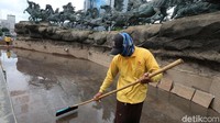 Sejumlah petugas tengah mengeringkan genangan air hujan di area kolam Patung Kuda Arjuna Wiwaha, Jakarta, Selasa (12/12/2017).