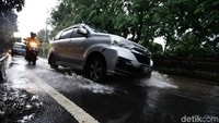 Pengendara mobil dan motor berjalan pelan untuk menghindari genangan.
