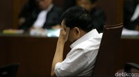 Novanto yang duduk di kursi terdakwa menutupi wajah dengan telapak tangannya.