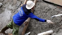Pekerja tengah membangun dinding kali.