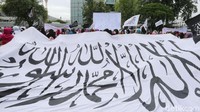 Massa aksi membawa puluhan bendera berwarna hitam dan putih. Ada juga dua bendera raksasa yang dibentangkan.