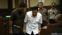 Novanto dituntun petugas menuju kursi terdakwa.