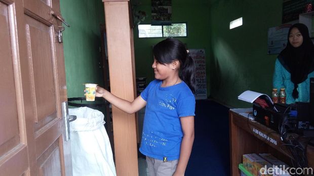 Salah seorang pengunjung memasukkan sampah plastik sebelum masuk ke perpustakaan.