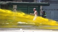 Petugas polisi membalas serangan demonstran dengan menyemprotkan air dari wator cannon. Air tersebut tampak berwarna kuning. Tak diketahui apa kandungan air berwana kuning itu/Foto: REUTERS/Agustin Marcarian