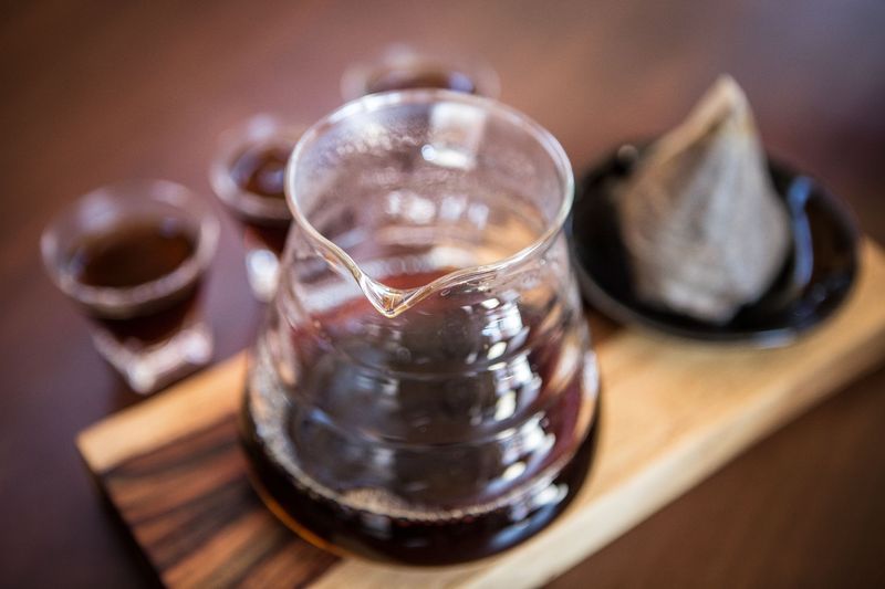 Fresh from the tap nitrous infused dark rich nitro black coffee in a glass jar java creamy beautiful froth foam head lifestyle decor with roasted beans on a rustic reclaimed wood wooden table background