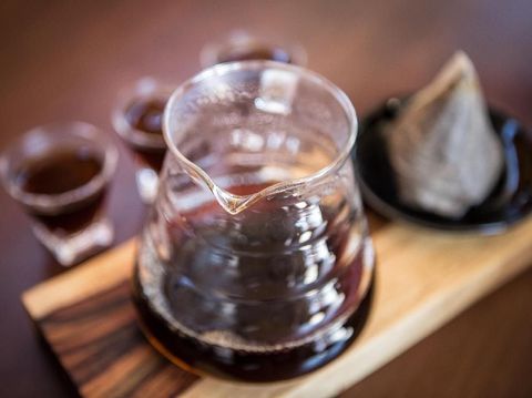 Fresh from the tap nitrous infused dark rich nitro black coffee in a glass jar java creamy beautiful froth foam head lifestyle decor with roasted beans on a rustic reclaimed wood wooden table background