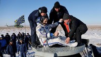 Astronot yang dibantu oleh tim untuk keluar dari kapsul saat mendarat di bumi.