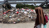 Pelajar melintasi di tumpukan sampah yang sudah berbau.