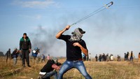 Seorang demonstran Palestina menggunakan ketapel untuk melemparkan batu ke arah tentara Israel yang menjaga perbatasan Gaza. Foto: REUTERS/Mohammed Salem