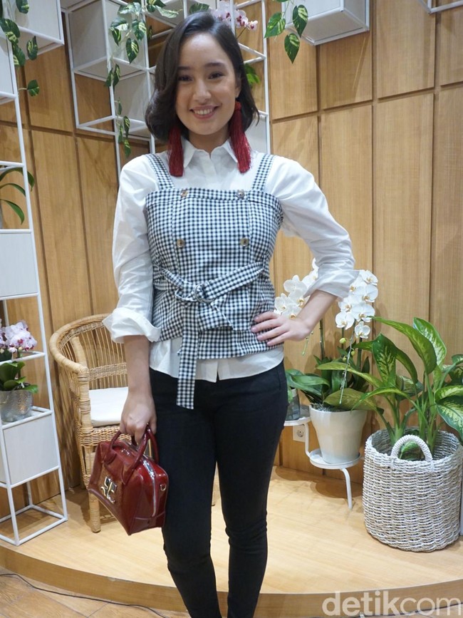Tatjana Saphira menebar pesonanya dengan kemeja putih berbalut korset model overall serta slim jeans hitam yang mempertegas figur rampingnya. Simpel namun chic. (Foto: Daniel Ngantung/Wolipop)