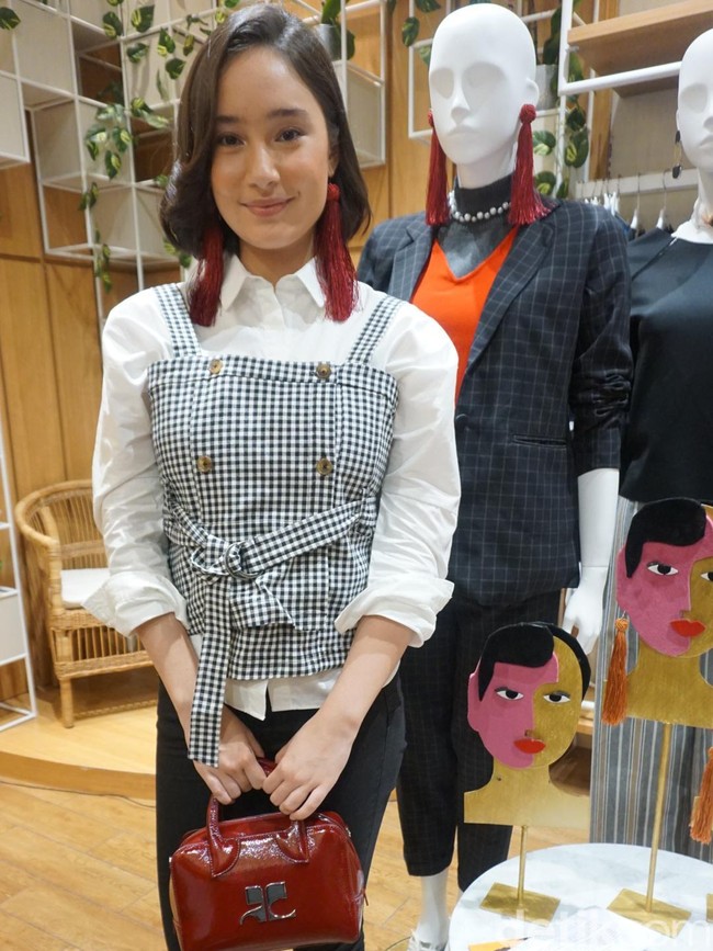 Menyempurnakan gayanya, sepasang statement earrings merah marun yang berhiaskan fringe atau rumbai. Tidak ketinggalan tas tangan model speedy bag berwarna senada. (Foto: Daniel Ngantung/Wolipop)