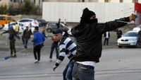 Terlihat demonstran Palestina di Tepi Barat melemparkan batu dengan ketapel ke arah tentara Israel. Militer Israel mengakui pihaknya memang melepas tembakan ke arah demonstran, namun tembakan ditargetkan kepada orang-orang yang menjadi provokator. Foto: AFP PHOTO/ABBAS MOMANI