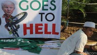 Sebuah spanduk bertuliskan Goes to Hell lengkap dengan wajah Presiden Amerika Donald Trump menaiki sepeda.