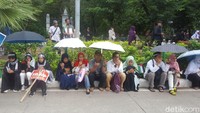 Massa berdoa sambil duduk di pinggir jalan dan menggunakan payung (Foto: Zunita Amalia Putri/detikcom)