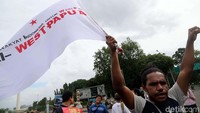 Seorang demonstran membentangkan bendera bertuliskan Papua Barat.