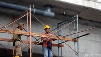 Dua orang pekerja memasang saluran air Flyover Cipinang Lontar.