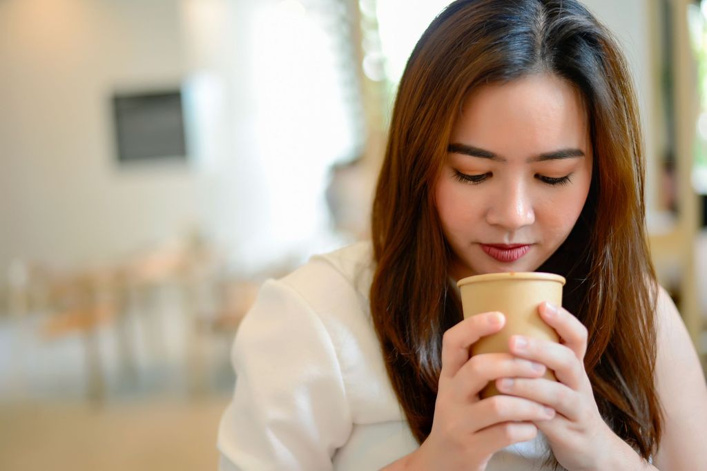 young chinese woman sitting next to windows in cafe.