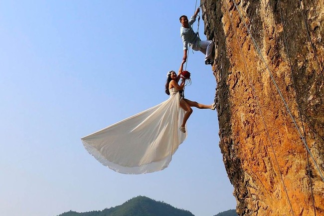 Pasangan asal China ini membuat sesi foto prewedding esktrem dengan berpose sambil bergelantungan di tebing. Adalah sang mempelai pria, Zheng Feng, yang memiliki ide foto tersebut karena dirinya hobi panjat tebing. Foto: Dok. Reuters