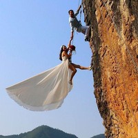 Pasangan asal China ini membuat sesi foto prewedding esktrem dengan berpose sambil bergelantungan di tebing. Adalah sang mempelai pria, Zheng Feng, yang memiliki ide foto tersebut karena dirinya hobi panjat tebing. Foto: Dok. Reuters