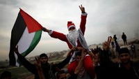 Demonstran berkostum sinterklas mengibarkan bendera Palestina bersama rekan-rekannya
