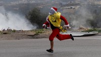 Demonstran berkostum sinterklas lari saat ada bentrokan dengan tentara Israel.
