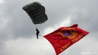 Prajurit Korps Marinir melayang-layang sambil mengibarkan bendera.