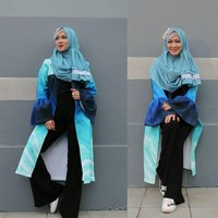 Gaya yang semarak diterapkan Okie Agustina kali ini. Lihat perpaduan setelan baju hitam dan outerwear berlengan lonceng yang bernuansa biru serta abstrak. Kerudung biru berenda dan headpiece di kepala tampak menarik perhatian. Foto: Dok. Instagram @mrs.gdc13