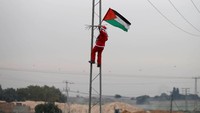 Demonstran itu naik tiang dan mengibarkan bendera Palestina