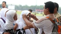 Petugas memakaikan kacamata kepada seorang warga.