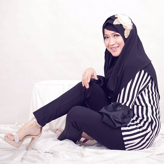 Okie Agustina tampil monokrom dengan perpaduan gaya hitam-putih memakai setelan celana dan striped blouse. Gaya hijabnya dibuat simpel dan polos. Ia menambahkan bros di atas kerudung yang menambah kesan elektrik.  Foto: Dok. Instagram @mrs.gdc13