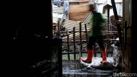 Sebagian petugas tampak mengeruk tanah di pinggir kali dan mengangkat tanah untuk menambal jalanan yang rusak terkena arus air.