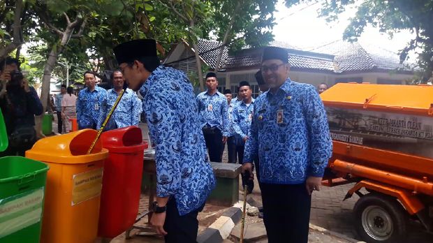 Sandiaga memungut sampah yang berserakan di jalanan di depan Kantor Bupati dan membuang ke tong sampah.
