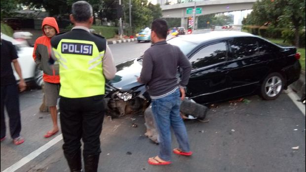 Petugas kepolisian melakukan penanganan kecelakaan mobil menabrak pembatas jalan di Semanggi