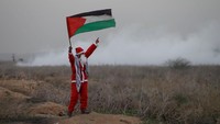 Santa mengibarkan bendera Palestina dalam aksi protes di perbatasan Israel kawasan timur kota Gaza. REUTERS/Mohammed Salem.